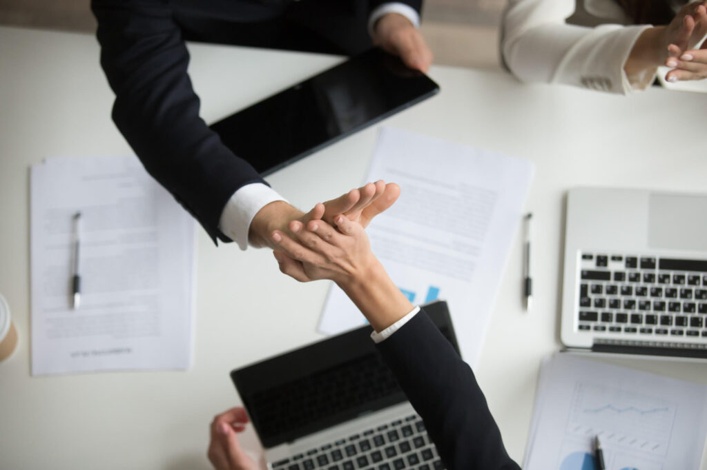 Close-up of hands exchanging documents during a VAT submission consultation in an office.