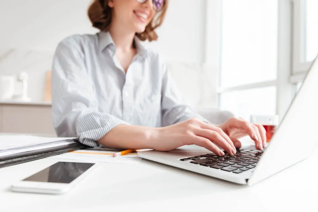 Smiling consultant entering PAYE registration details on a computer in a modern office.