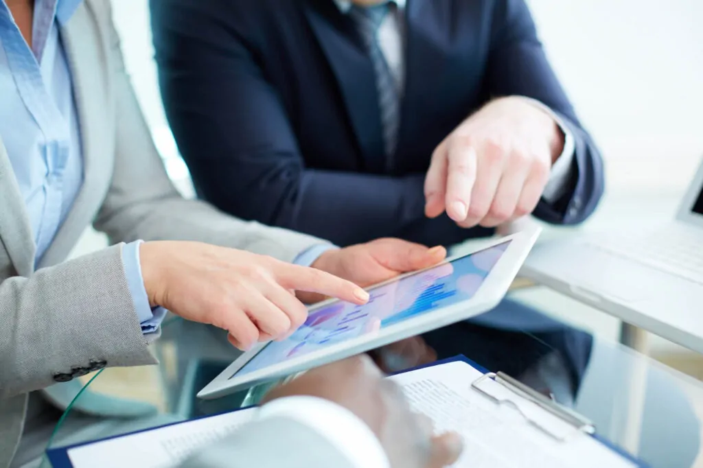 Experts discussing CIS 20 deduction details using a tablet for data analysis in an office setting.
