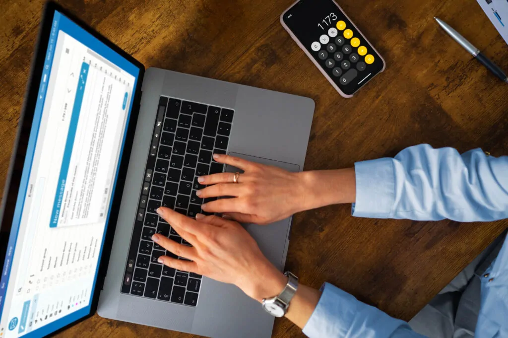 Hands typing on a laptop during the preparation of VAT submission reports and calculations.