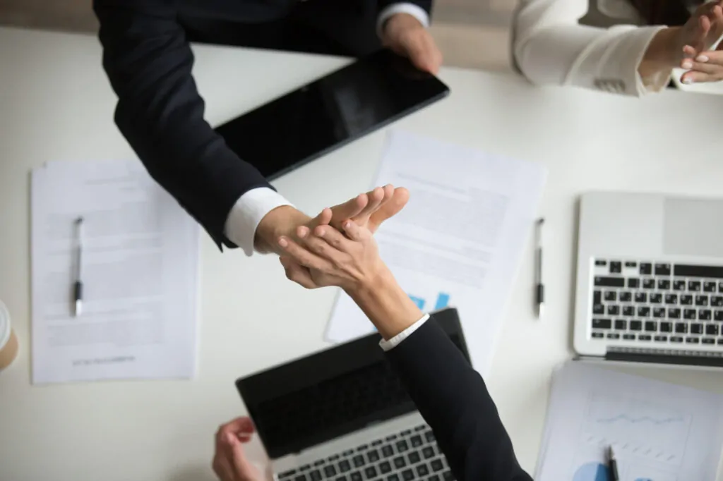 Close-up of hands exchanging documents during a VAT submission consultation in an office.