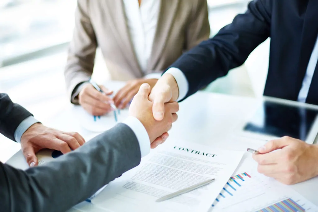 Executives shaking hands after finalising VAT submission details and agreements.