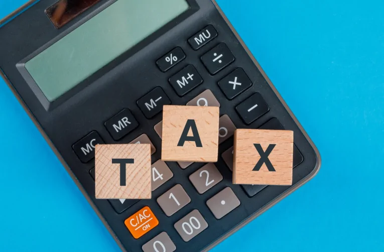 Calculator with wooden TAX letters – Expert tax filing and income tax services by Audit Consulting Group UK